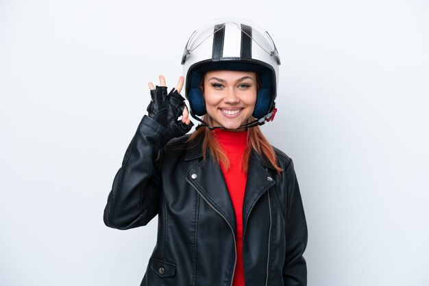 Jovem russa com um capacete de moto isolado no fundo branco, mostrando sinal de ok com os dedos
