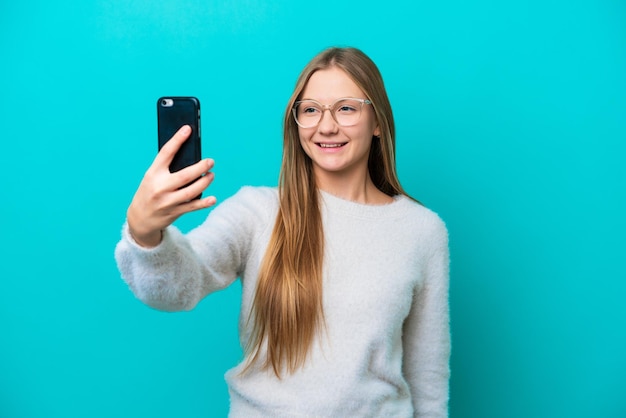 Jovem russa isolada em fundo azul fazendo uma selfie