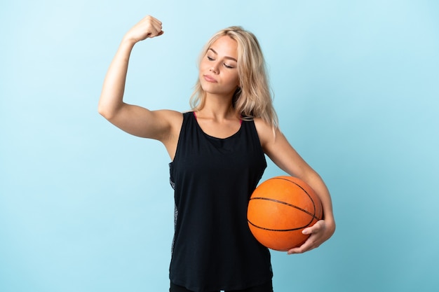 Jovem russa jogando basquete isolada em azul fazendo um gesto forte