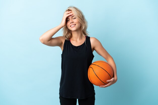 Jovem russa jogando basquete isolada no azul e sorrindo muito