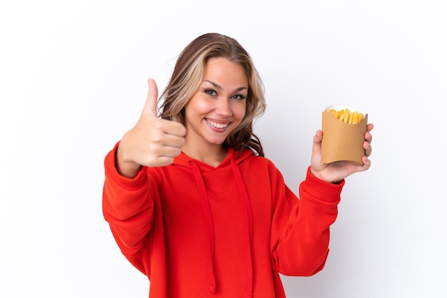 Jovem russa segurando batatas fritas isoladas em fundo branco com polegares para cima porque algo bom aconteceu