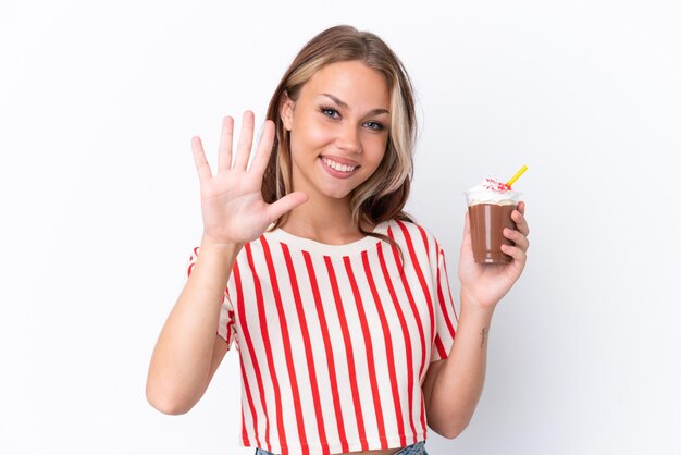 Jovem russa segurando cappuccino isolado no fundo branco contando cinco com os dedos