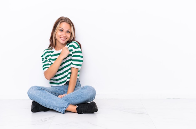 Jovem russa sentada no chão isolada no fundo branco comemorando uma vitória