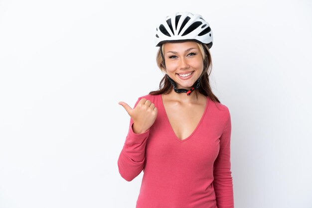 Jovem russa usando um capacete de bicicleta isolado no fundo branco apontando para o lado para apresentar um produto