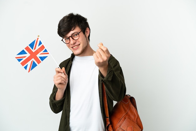 Jovem russo segurando uma bandeira do reino unido, isolada no fundo branco, fazendo gesto de dinheiro