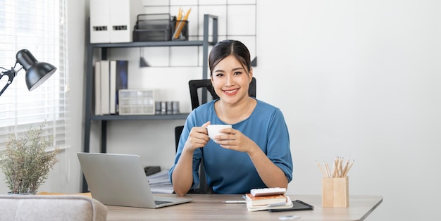 Jovem satisfeita feliz alegre bonita mulher de negócios bonita sentar-se no escritório em casa relaxando com café quente