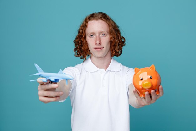 Jovem satisfeito segurando avião de brinquedo com porco isolado em fundo azul