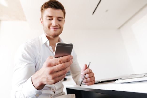 Jovem satisfeito usando telefone celular