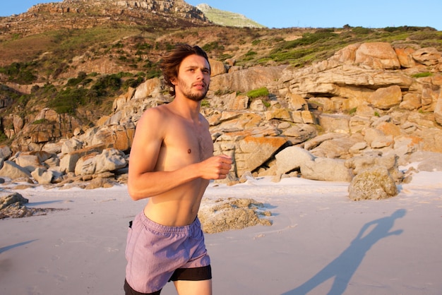 Jovem saudável correndo na praia