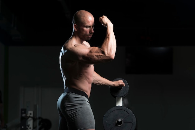 Jovem saudável em pé forte na academia e flexionando os músculos Muscular Atlético Fisiculturista Modelo de fitness posando após exercícios