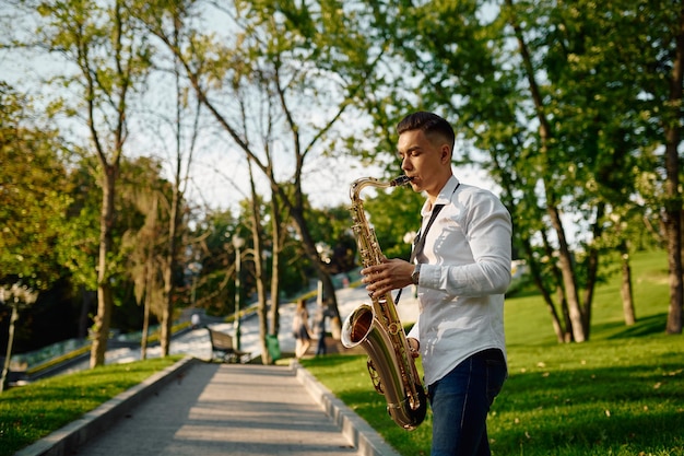 Foto jovem saxofonista tocando saxofone no parque