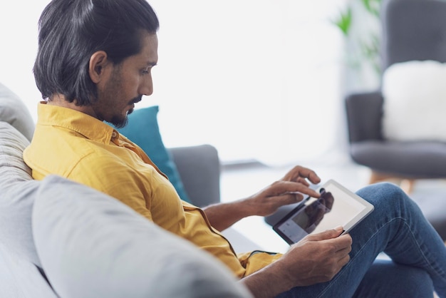 Jovem se conectando com um tablet digital em casa