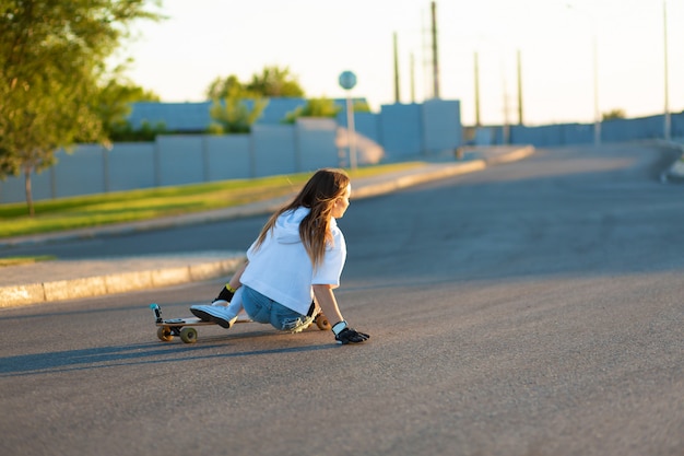 Jovem se divertindo com o skate na estrada.