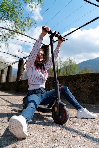 Jovem se divertindo com uma camisa e fones de ouvido e andando de scooter em um parque