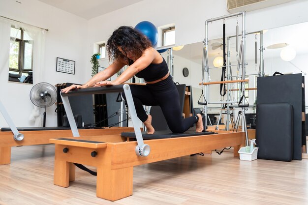 Jovem se exercitando em camas de reformadores de pilates