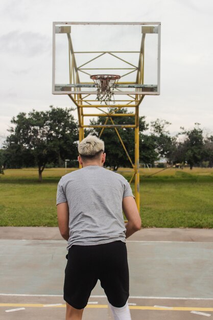 Jovem se preparando para atirar em uma quadra de basquete abandonada.