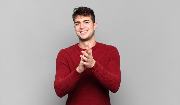 Jovem se sentindo feliz e bem-sucedido, sorrindo e batendo palmas, dizendo parabéns com um aplauso