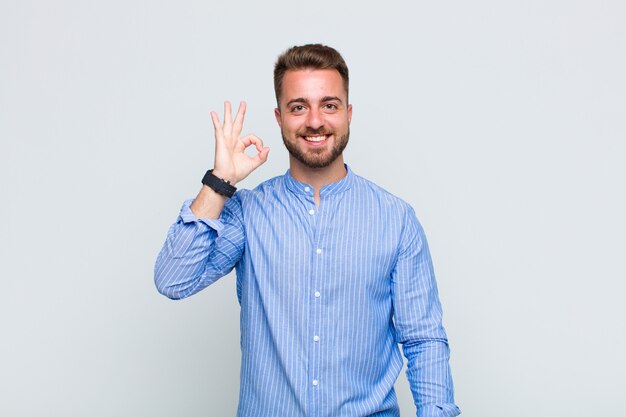 Jovem se sentindo feliz, relaxado e satisfeito, mostrando aprovação com gesto de ok, sorrindo