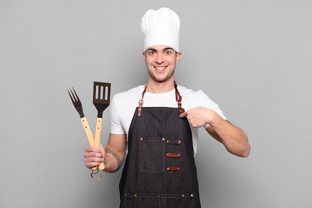 Jovem se sentindo feliz, surpreso e orgulhoso, apontando para si mesmo com um olhar animado e surpreso