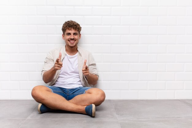 Foto jovem se sentindo feliz, tranquilo, satisfeito, relaxado e bem-sucedido, apontando para frente, escolhendo você