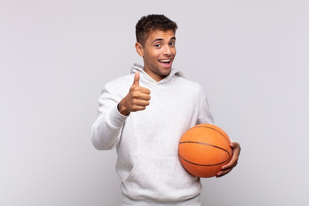 Jovem se sentindo orgulhoso, despreocupado, confiante e feliz, sorrindo positivamente com o polegar para cima. conceito de cesta