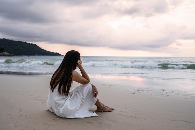 Jovem se sentindo sozinha e triste olhando para o mar em um dia sombrio