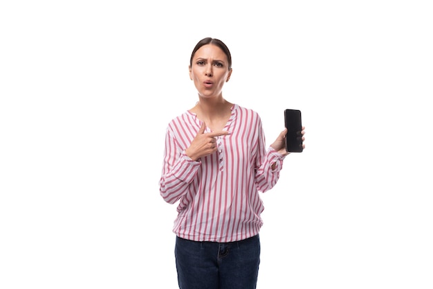 Jovem secretária morena com cabelo de rabo de cavalo vestida com blusa listrada mostra smartphone
