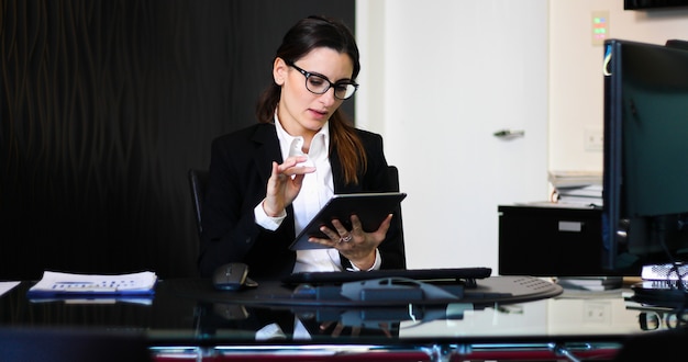 Jovem secretária pensativa usando um tablet digital na mesa dela