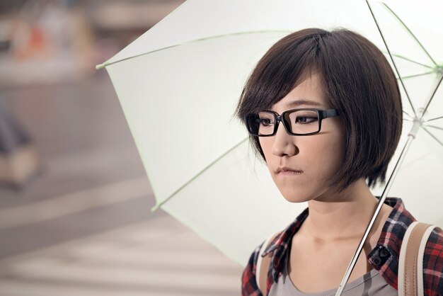 Jovem segura guarda-chuva e fica na rua em taipei, taiwan.