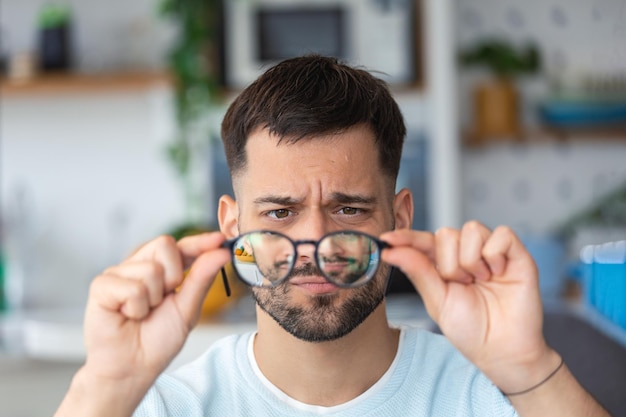 Jovem segura óculos com lentes de dioptria e olha através deles o problema da correção da visão da miopia