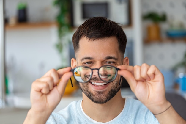 Jovem segura óculos com lentes de dioptria e olha através deles o problema da correção da visão da miopia