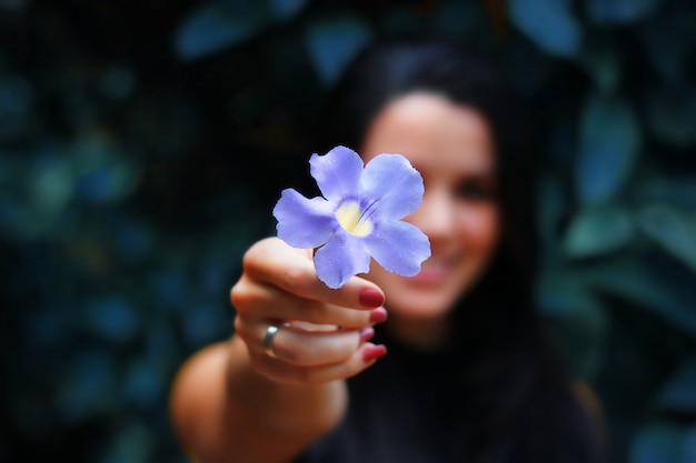 Foto jovem, segurando a flor lilás na bela paisagem