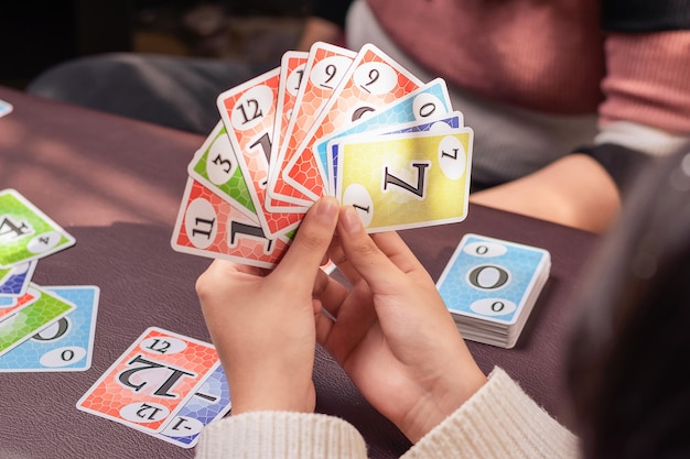 Jovem segurando cartas de jogo de tabuleiro no conforto de sua casa