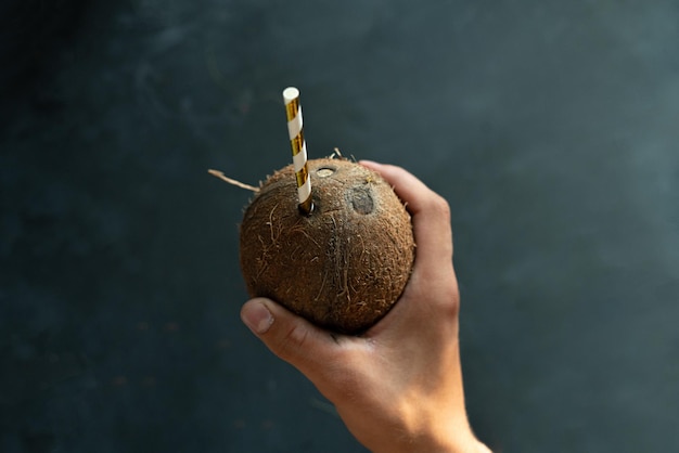 Jovem segurando coco com um canudo e bebendo de perto