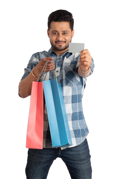 Jovem segurando e posando com sacolas de compras com cartão de crédito ou débito em um fundo branco