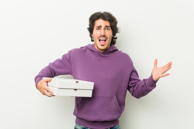 Jovem, segurando o pacote de pizzas comemorando uma vitória ou sucesso