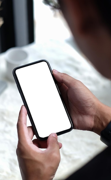 Jovem segurando o telefone inteligente de maquete com tela branca em branco para montagem de exibição gráfica