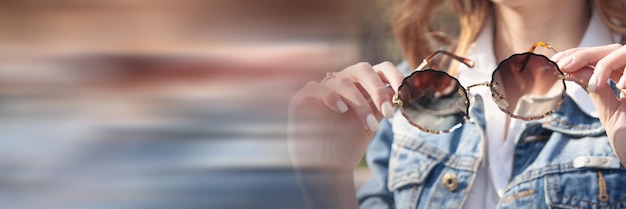 Jovem segurando óculos de sol ao ar livre