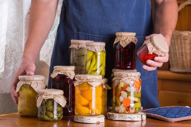 Jovem segurando potes com comida caseira em conserva e fermentada, em conserva e marinada. preservação da colheita, produtos locais dos agricultores