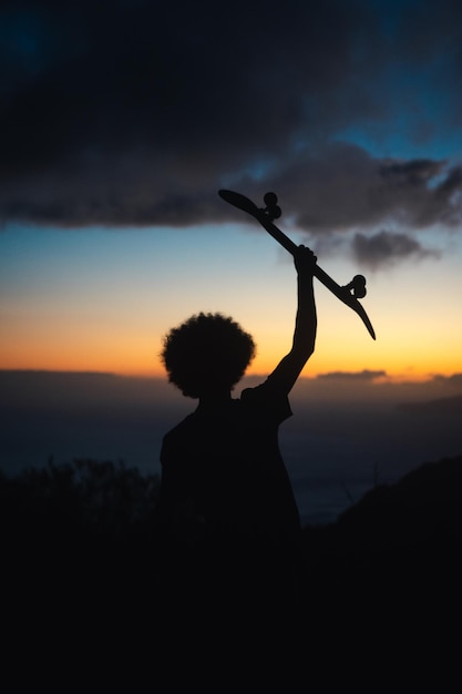 Foto jovem segurando seu patins durante o pôr-do-sol