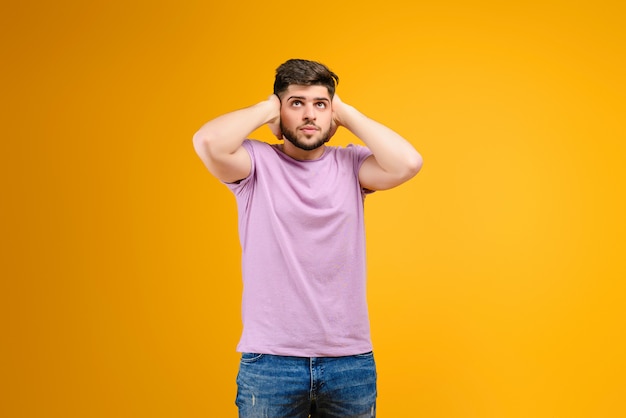 Jovem, segurando sua cabeça isolada sobre fundo amarelo