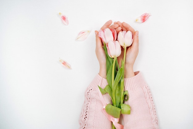 Jovem segurando um buquê de tulipas cor de rosa. Vista superior, fundo branco, espaço de cópia de texto.