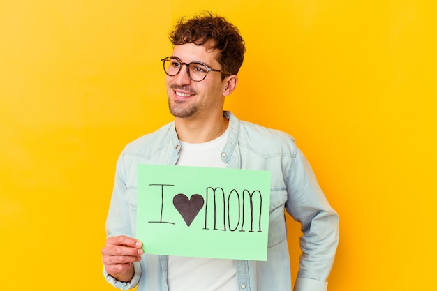 Jovem segurando um cartaz de proteja nosso planeta isolado olha de lado sorrindo, alegre e agradável