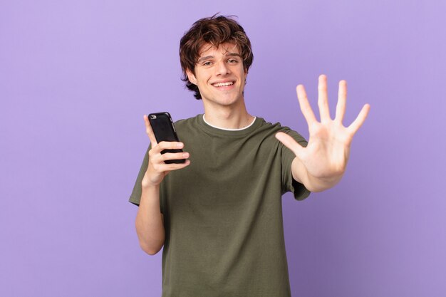 Jovem segurando um celular sorrindo e parecendo amigável, mostrando o número cinco