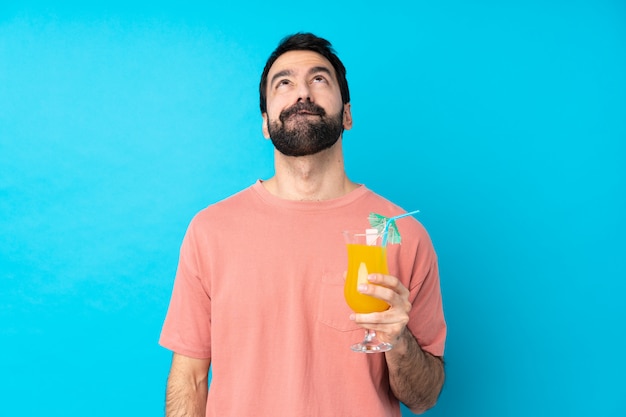 Jovem, segurando um cocktail sobre azul isolado