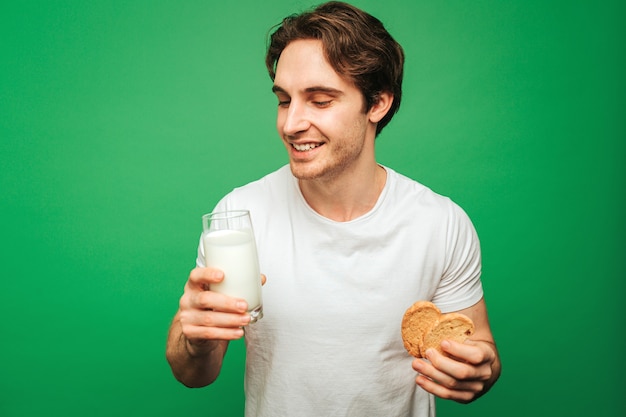 Jovem segurando um copo de leite com biscoitos