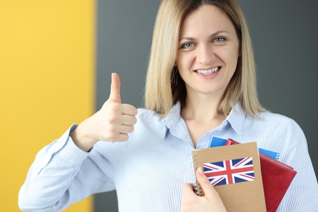 Jovem segurando um livro de inglês e mostrando o polegar