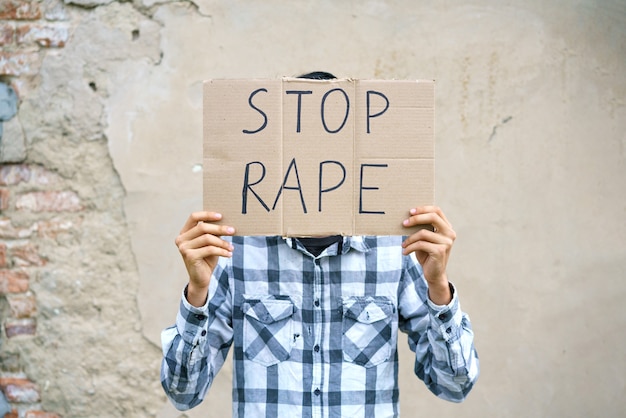 Jovem segurando um papelão com a inscrição parar estuprar cara de aparência caucasiana contra viole ...