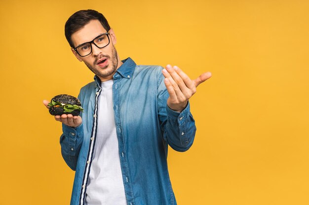 Foto jovem segurando um pedaço de hambúrguer estudante come fast-food hambúrguer não é comida útil