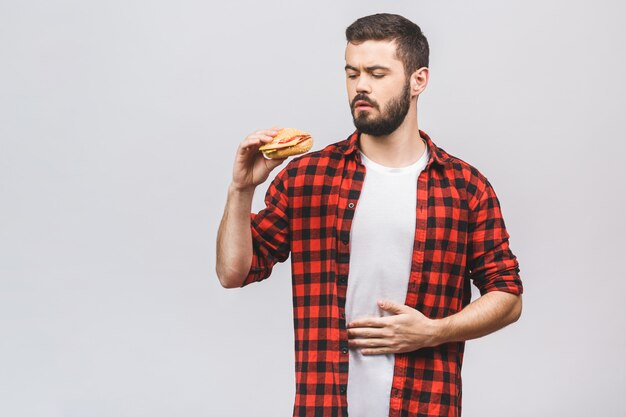 Jovem, segurando um pedaço de hambúrguer. Faça dieta o conceito isolado contra o fundo branco.